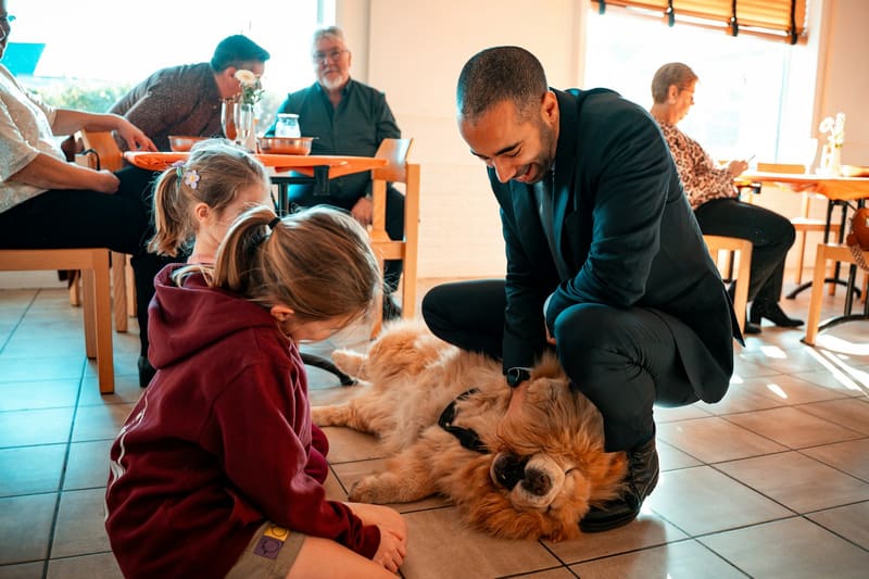 Un adulte et un enfant caressent un chien à la maison